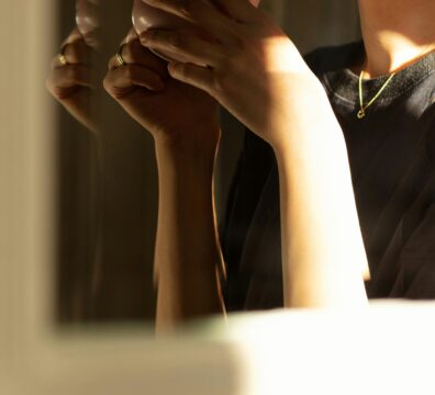 A person holds a ceramic cup close to their face in warm dramatic light, eyes partially visible, capturing the quiet inward experience of living with anxiety that feels like personality.